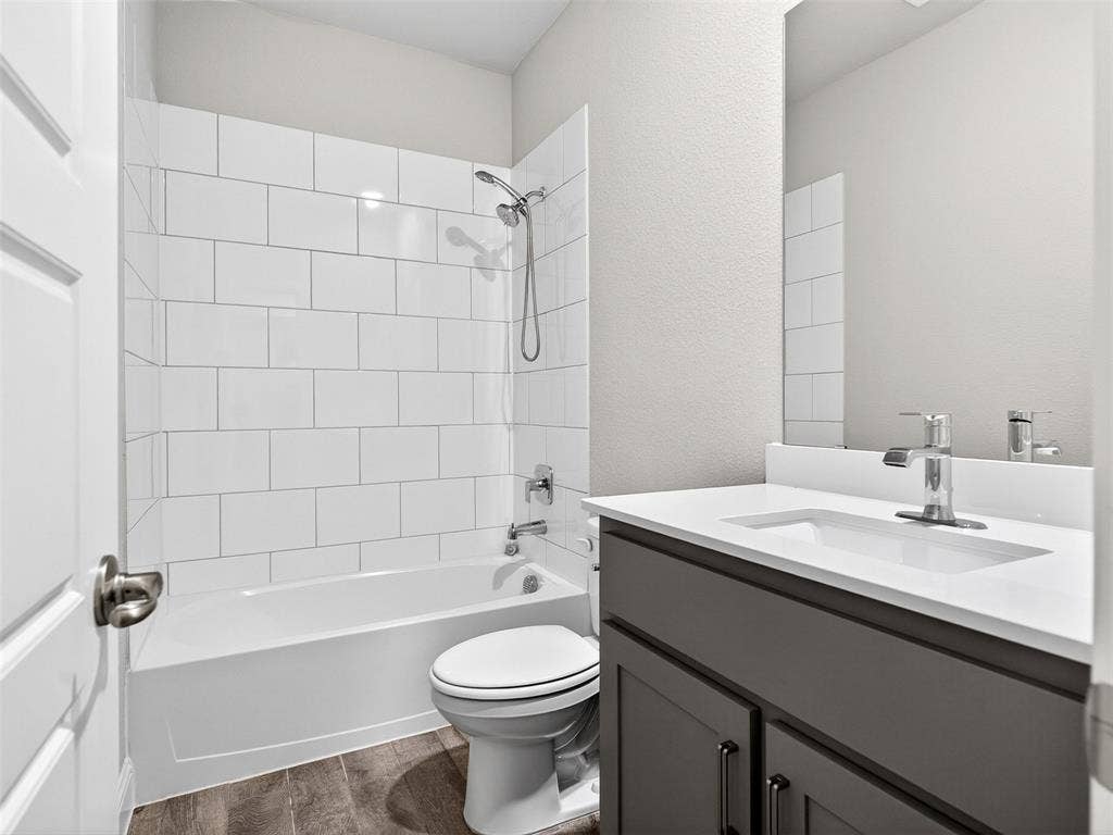 2504 Wren Lane, Denton, TX 76205 Tub/shower combination with white subway tile surround, single vanity with a white countertop, and wood-finish flooring