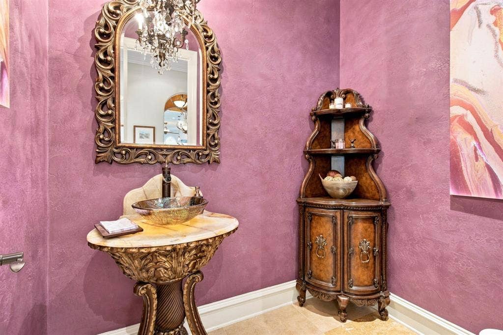 Ornate carved wood vanity with a vessel sink and stone countertop