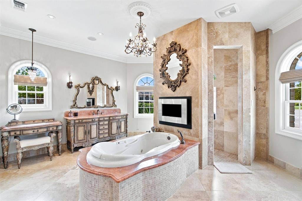 Freestanding jetted bathtub with a mosaic tile surround and red countertop