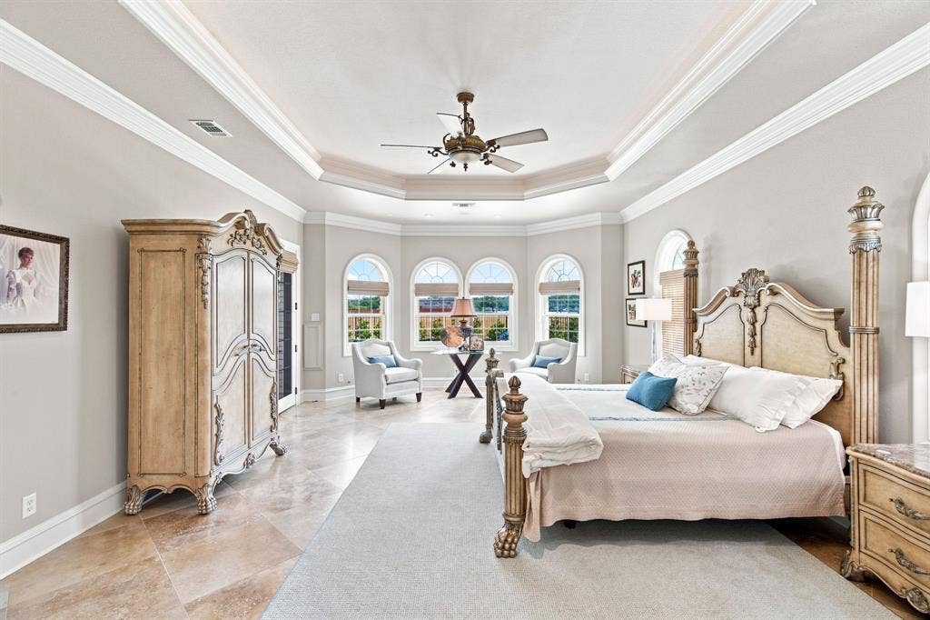 Tray ceiling with crown molding, arched windows, and tile flooring