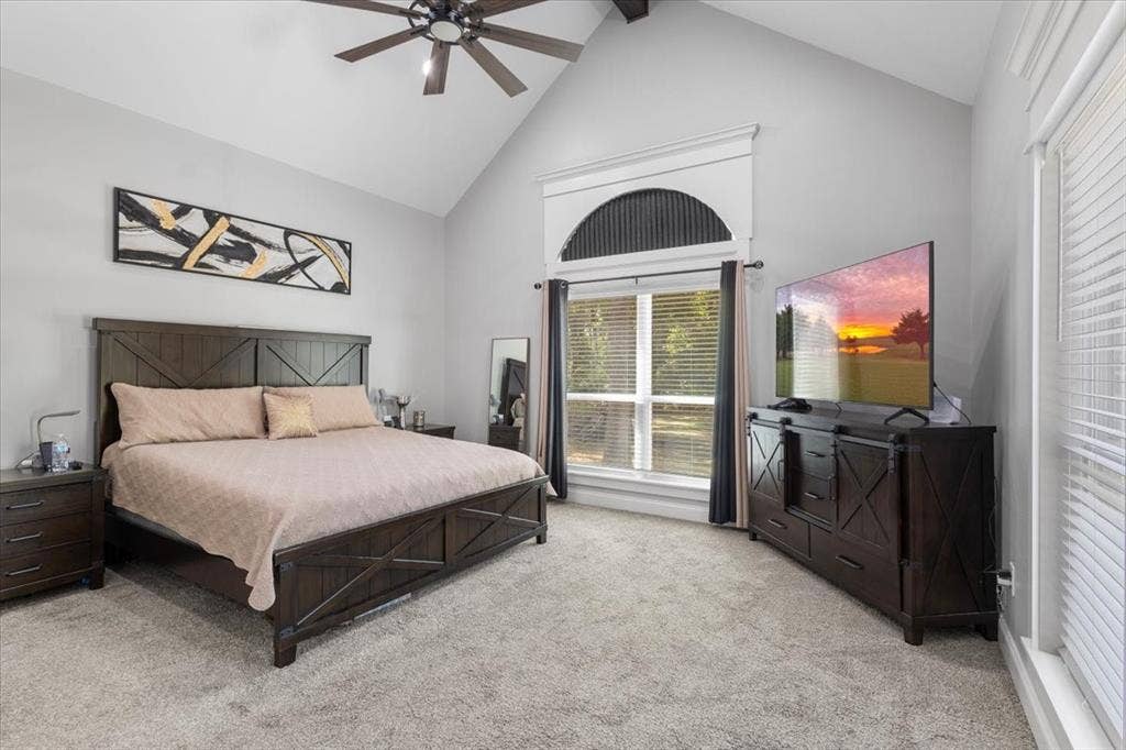16136 County Road 1134=, Tyler, TX 75709 Vaulted ceiling with a ceiling fan, arched window with decorative trim, multiple windows with blinds, and light-colored carpeting