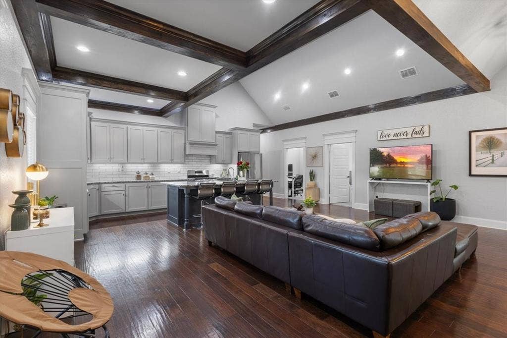 16136 County Road 1134=, Tyler, TX 75709 Vaulted ceiling with dark wood-finish beams, recessed lighting, wood-finish flooring, light grey cabinetry, and a kitchen island with seating