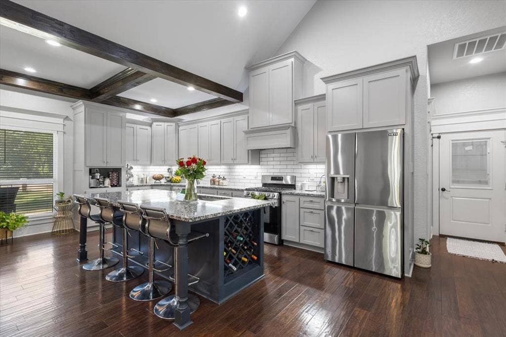 16136 County Road 1134=, Tyler, TX 75709 Vaulted ceiling with exposed wood beams, stainless steel appliances, wood-finish flooring, white subway tile backsplash, and an island with built-in wine storage