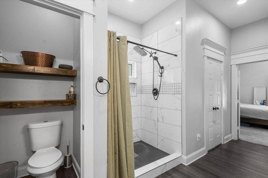 16136 County Road 1134=, Tyler, TX 75709 Walk-in shower with large format wall tiles and mosaic accent, dark flooring, and a floating wood shelf storage