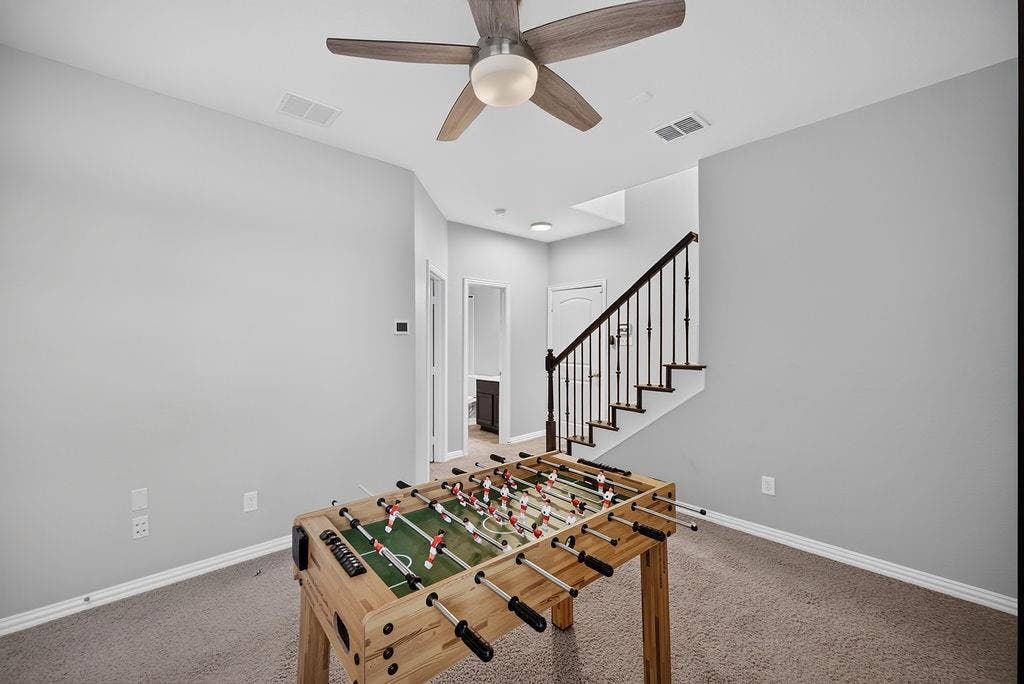 7880 Oxer Drive, Irving, TX 75063 Carpeted area with a ceiling fan, recessed lighting, and a staircase featuring dark wood treads and wrought iron balusters