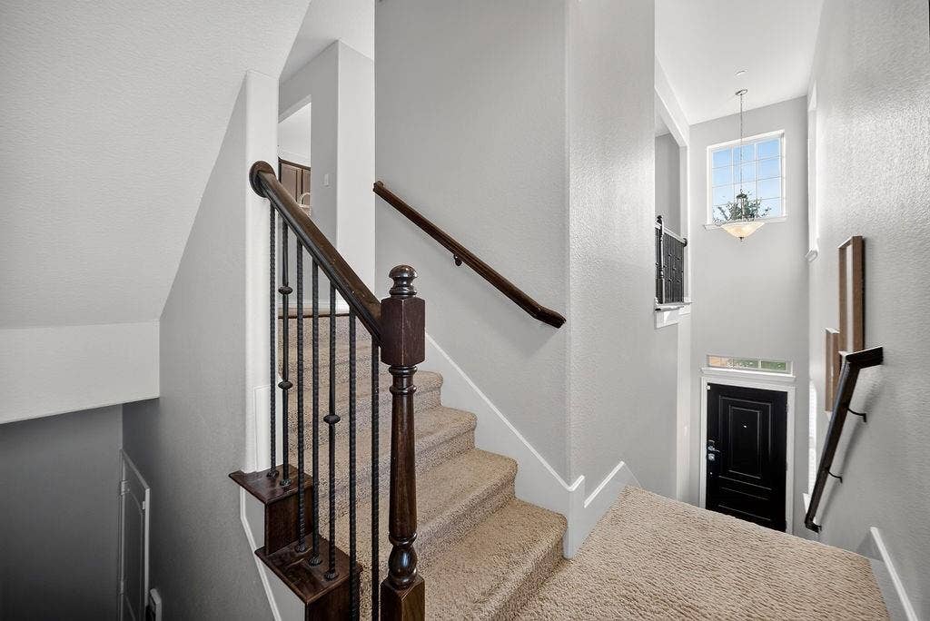 7880 Oxer Drive, Irving, TX 75063 Carpeted staircase with dark wood-finish handrails and wrought iron balusters
