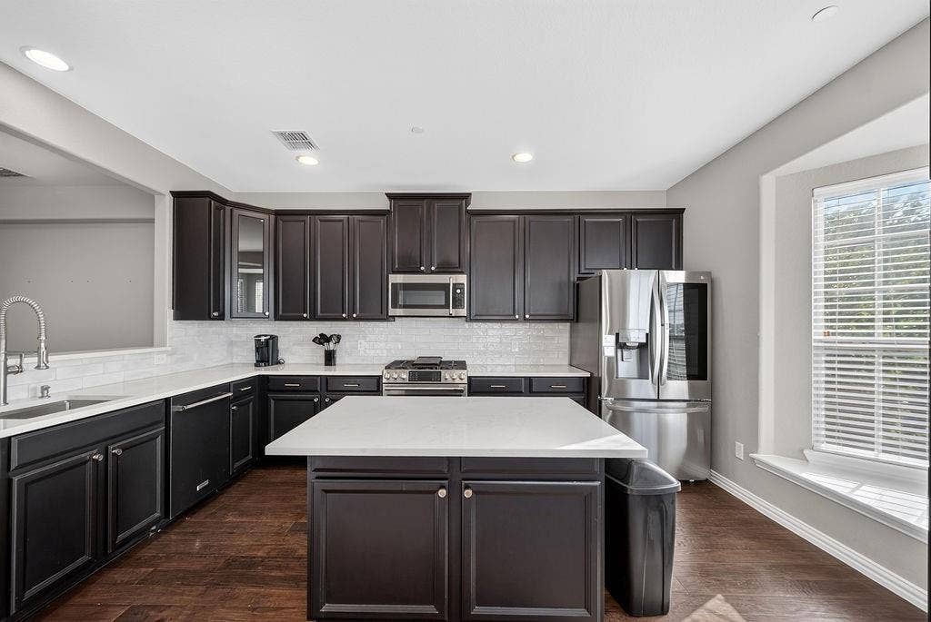 7880 Oxer Drive, Irving, TX 75063 Kitchen featuring dark wood-finish cabinetry, white countertops, white subway tile backsplash, and stainless steel appliances