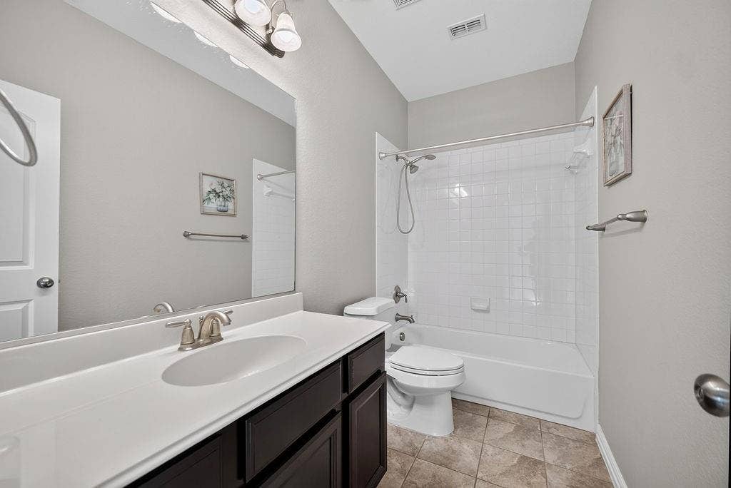 7880 Oxer Drive, Irving, TX 75063 Dark wood-finish vanity with an integrated sink, brushed nickel faucet, and a large wall-mounted mirror