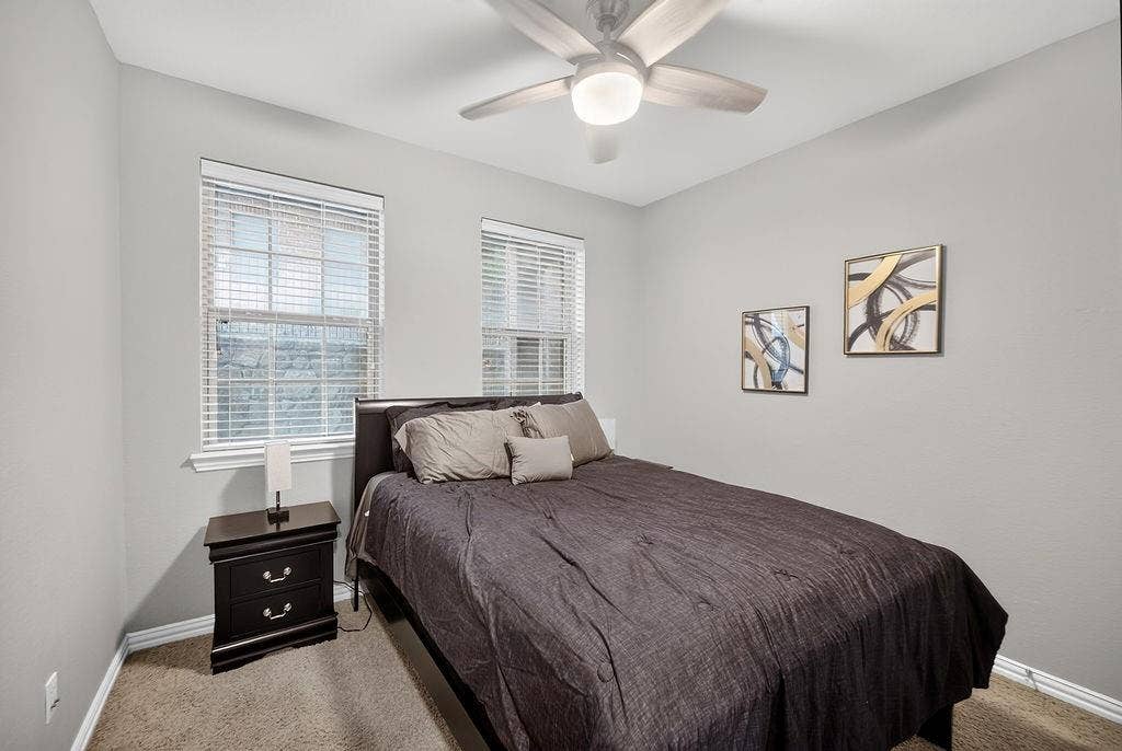 7880 Oxer Drive, Irving, TX 75063 Neutral wall color, two windows with blinds, ceiling fan with light fixture, carpeted flooring, and white trim