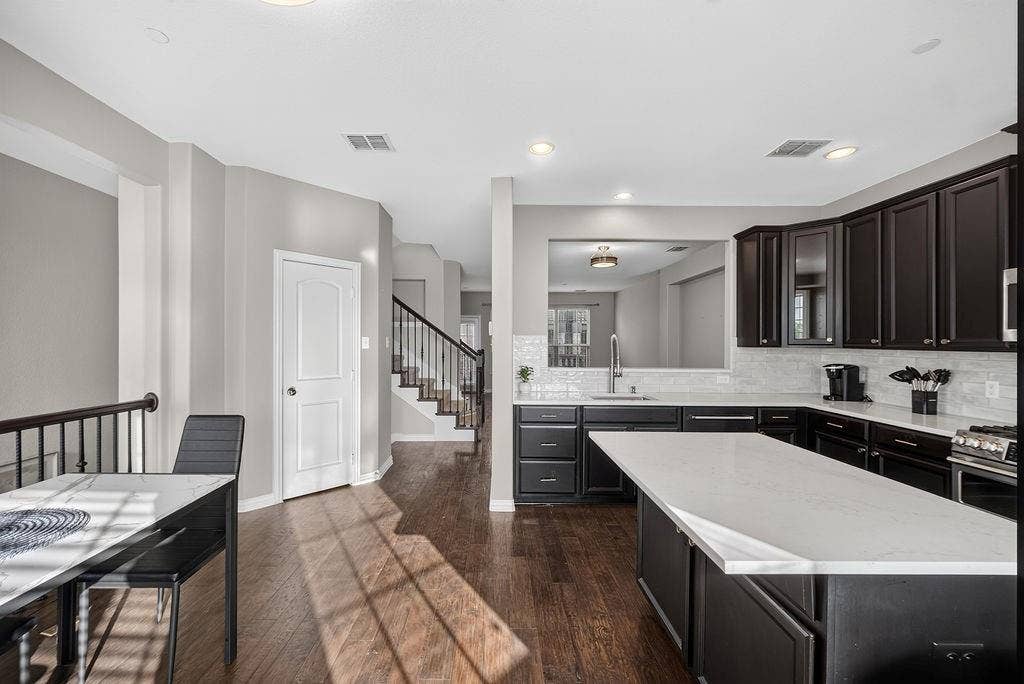 7880 Oxer Drive, Irving, TX 75063 Kitchen with dark wood cabinetry, light countertops, and a full tile backsplash