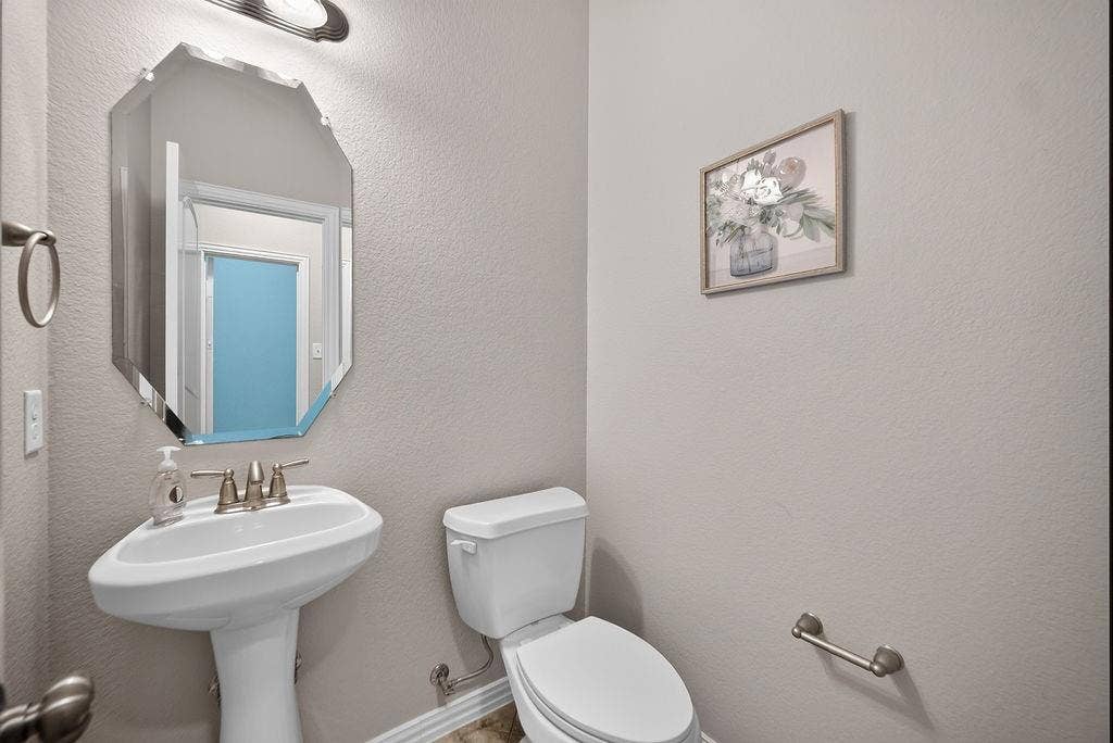 7880 Oxer Drive, Irving, TX 75063 Pedestal sink with brushed nickel faucet, beveled wall mirror, and neutral wall paint