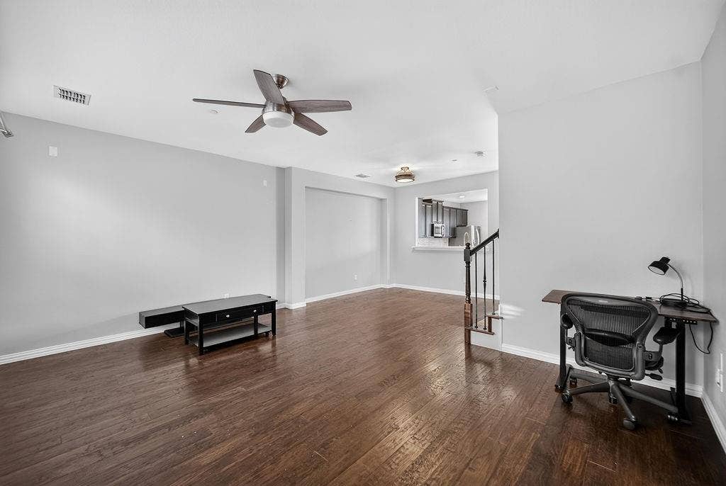 7880 Oxer Drive, Irving, TX 75063 Hardwood-finish flooring, ceiling fan, and staircase with dark balusters