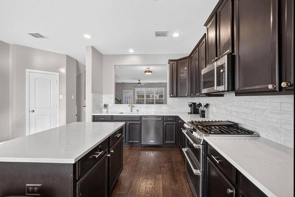 7880 Oxer Drive, Irving, TX 75063 Spacious kitchen featuring dark wood cabinetry, light-toned countertops, and stainless steel appliances including a gas range and built-in microwave