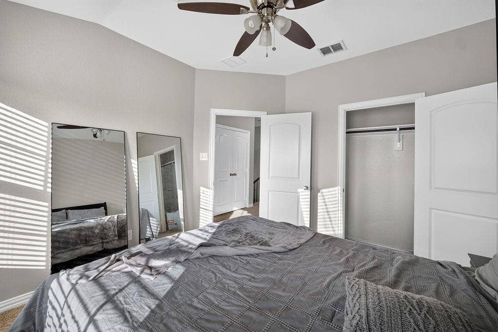 7880 Oxer Drive, Irving, TX 75063 Vaulted ceiling with a ceiling fan, light gray wall paint, open closet with hanging rod, and two paneled interior doors