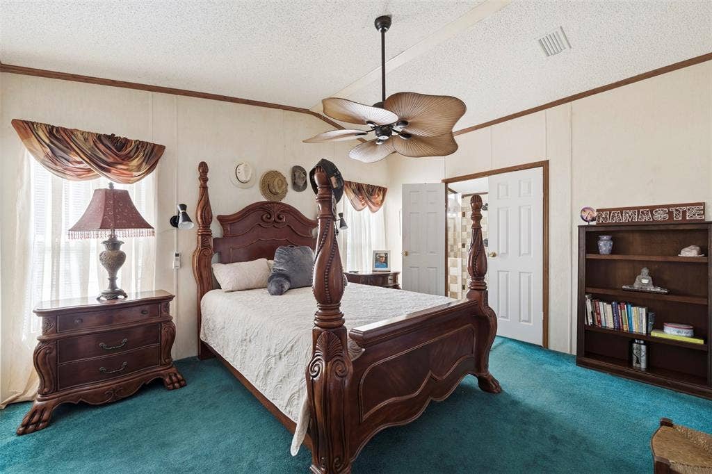 18404 Pine Drive, Eustace, TX 75124 Ceiling fan with unique blade design, white paneled walls with wood trim, light-colored window treatments, and teal carpet flooring