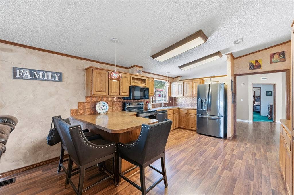 18404 Pine Drive, Eustace, TX 75124 Kitchen featuring wood-finish flooring, natural wood cabinetry, stainless steel appliances, and a breakfast bar