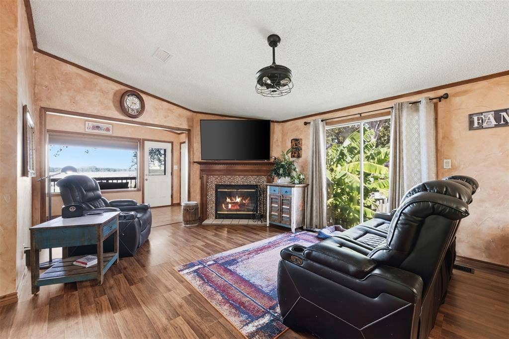 18404 Pine Drive, Eustace, TX 75124 Spacious living area featuring hardwood flooring, a fireplace with decorative surround, built-in cabinetry, and a ceiling-mounted light fixture
