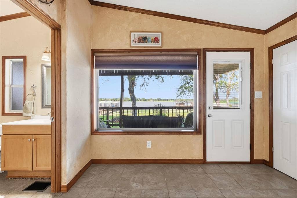 18404 Pine Drive, Eustace, TX 75124 Tiled flooring, wood-finish trim, built-in vanity with cabinetry, and an exterior door with a window panel