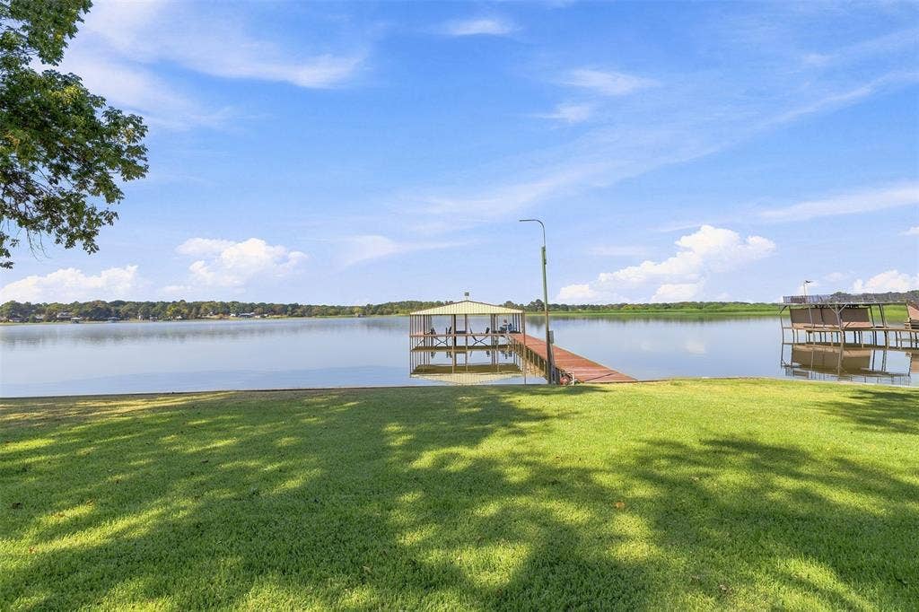 18404 Pine Drive, Eustace, TX 75124 Expansive waterfront property featuring a covered boat dock, extended wooden pier, and an additional open dock structure