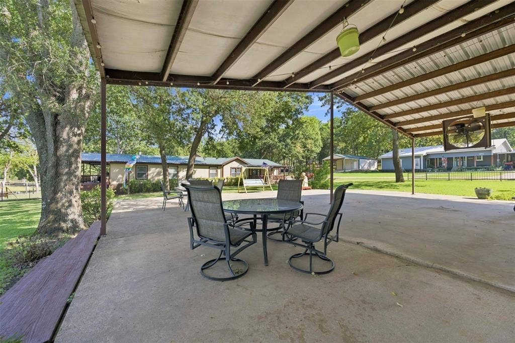 18404 Pine Drive, Eustace, TX 75124 Expansive concrete patio with a metal roof covering, supported by metal posts, and integrated lighting fixtures