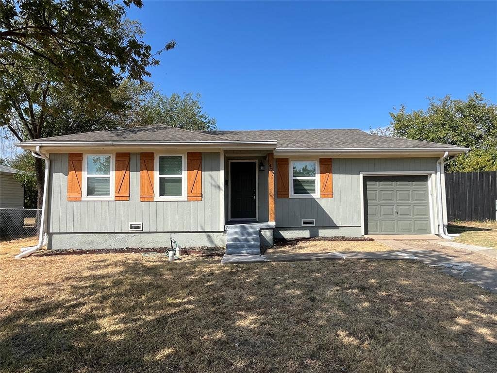 427 NE 38th Street, Grand Prairie, TX 75050 Exterior featuring horizontal siding, wood-look window shutters, a dark entry door, and an attached garage with a panel door