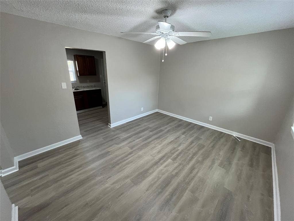 427 NE 38th Street, Grand Prairie, TX 75050 Wood-finish flooring with light gray walls, white trim, and a ceiling fan with integrated lighting