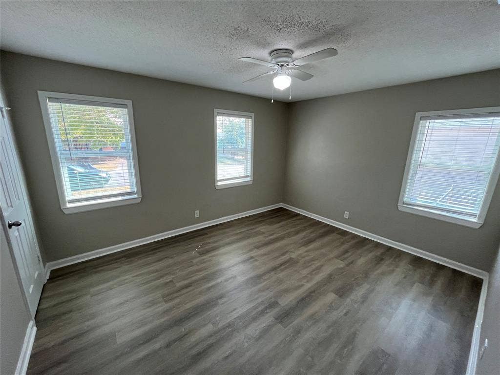427 NE 38th Street, Grand Prairie, TX 75050 Contemporary ceiling fan with integrated lighting, wood-finish flooring, multiple windows with blinds, and neutral painted walls