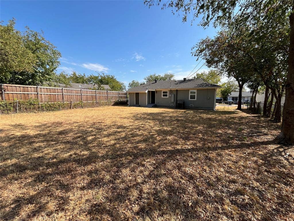 427 NE 38th Street, Grand Prairie, TX 75050 Spacious backyard with privacy fencing, mature trees, and a single-story residence