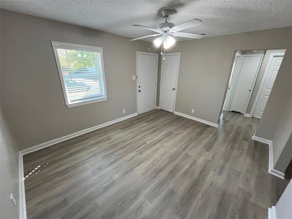 427 NE 38th Street, Grand Prairie, TX 75050 Gray wood-finish flooring, white ceiling fan with integrated lighting, window with blinds, and neutral wall paint