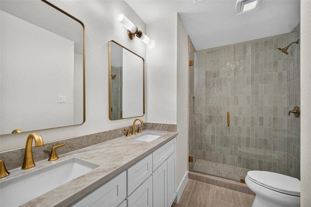 3041 Hillingdon Drive, Richardson, TX 75082 Double vanity with undermount sinks, gold-tone fixtures, and framed mirrors