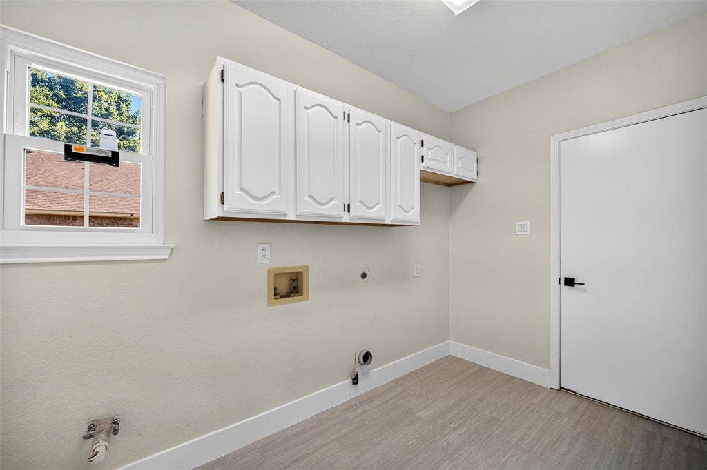 3041 Hillingdon Drive, Richardson, TX 75082 White cabinetry, wood-finish flooring, white door with black hardware, and a window with natural light