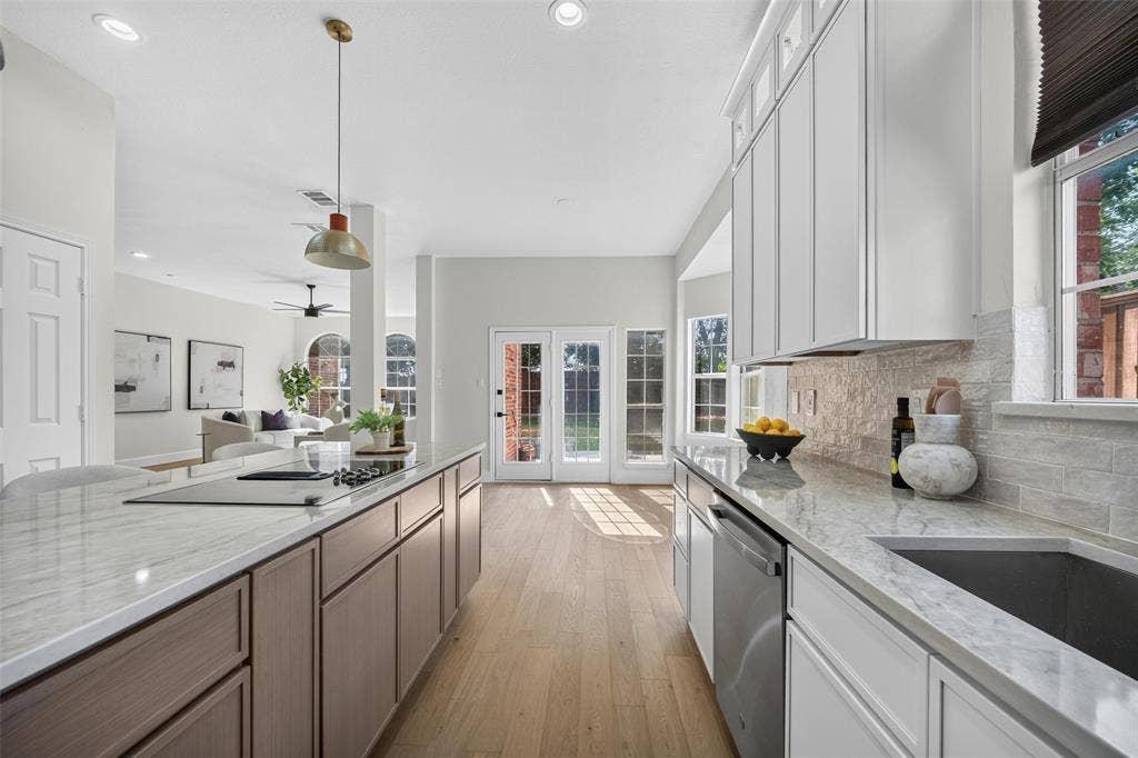 3041 Hillingdon Drive, Richardson, TX 75082 Kitchen featuring light wood-finish flooring, recessed lighting, an expansive island with a built-in cooktop, light-toned countertops, and white cabinetry