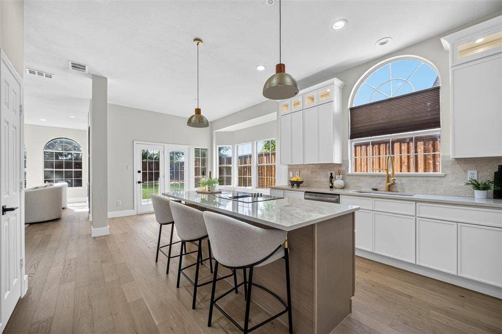 3041 Hillingdon Drive, Richardson, TX 75082 Kitchen with an island featuring a cooktop and stone countertop, white shaker-style cabinetry, wood-finish flooring, and French doors leading to the exterior