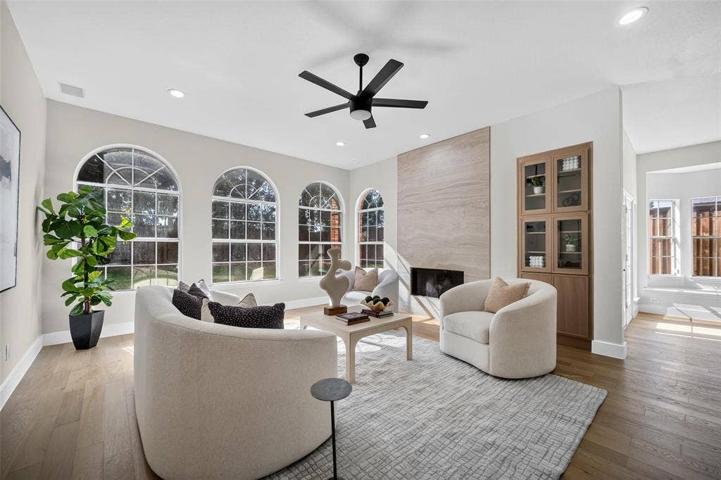 3041 Hillingdon Drive, Richardson, TX 75082 Arch-top windows, wood-finish flooring, recessed lighting, built-in cabinetry with glass doors, and a stone-clad fireplace