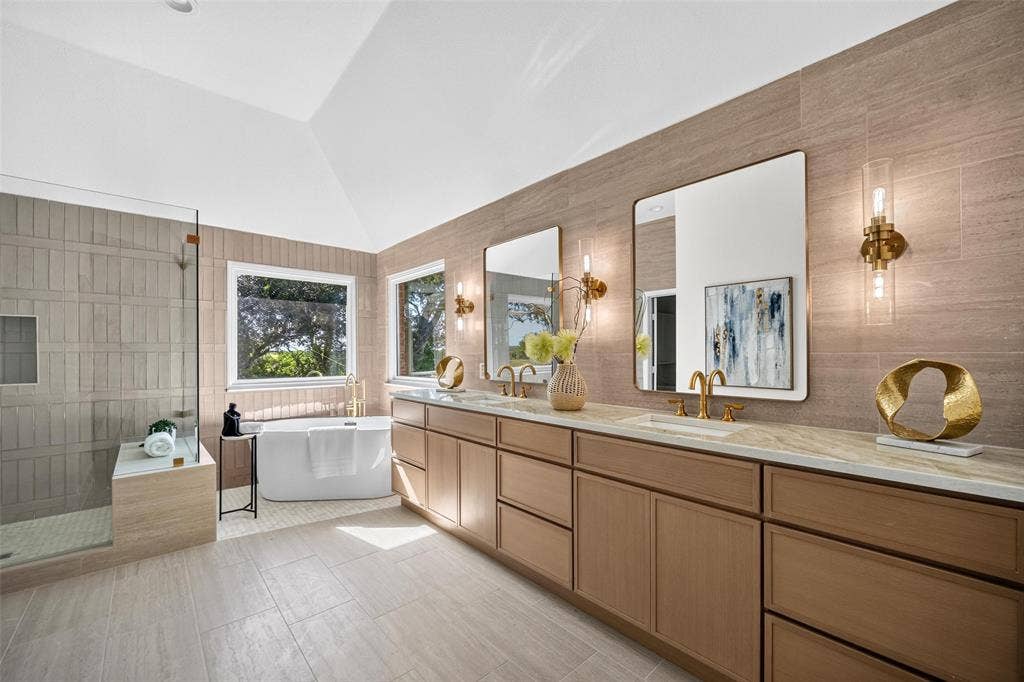 3041 Hillingdon Drive, Richardson, TX 75082 Vaulted ceiling with recessed lighting, double vanity with wood-finish cabinetry, frameless mirrors with wall sconces, freestanding soaking tub, and a glass-enclosed shower with bench seating