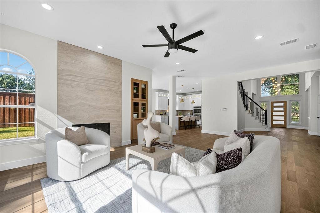 3041 Hillingdon Drive, Richardson, TX 75082 Spacious living area featuring a wood-finish flooring, a contemporary fireplace with a stone surround, recessed lighting, and a modern ceiling fan