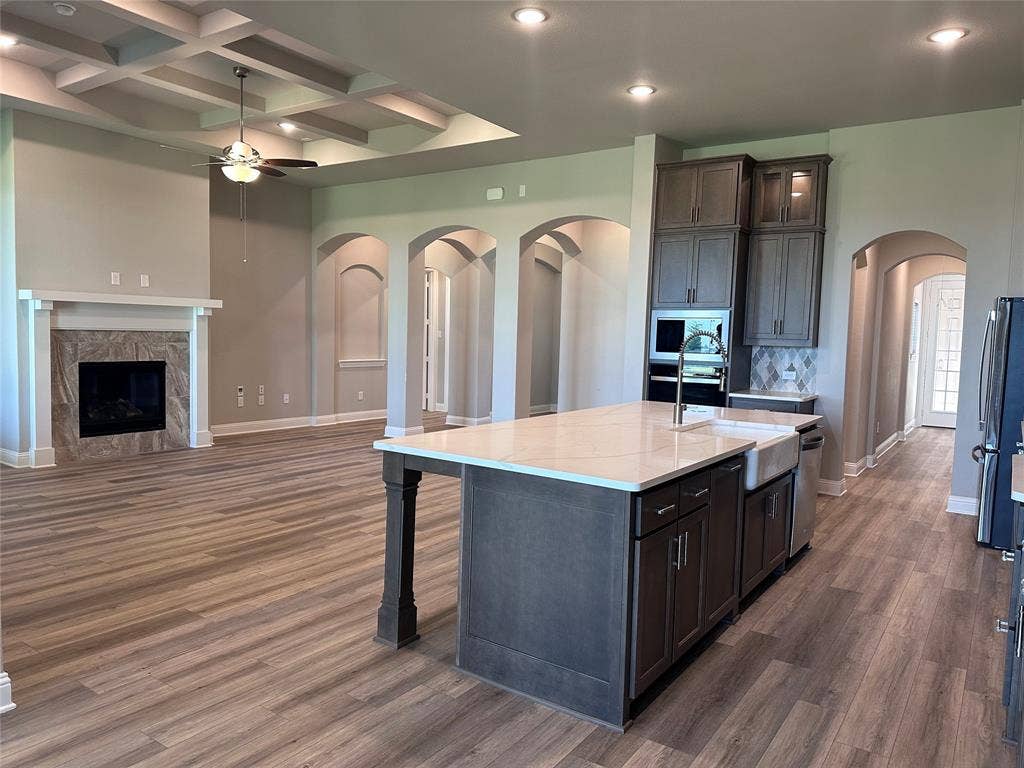 2608 Roaming Trail, Northlake, TX 76247 Open-concept living area with wood-finish flooring, a coffered ceiling, and a fireplace with a stone surround