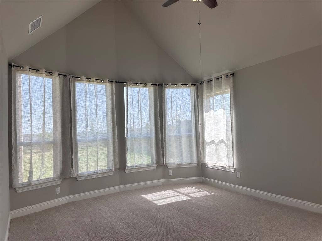 2608 Roaming Trail, Northlake, TX 76247 Vaulted ceiling room featuring a ceiling fan, five large windows, and neutral carpeting