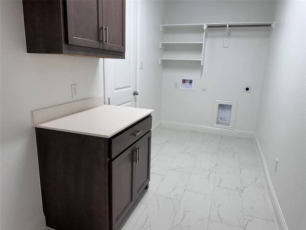 2608 Roaming Trail, Northlake, TX 76247 White tile flooring, dark wood-finish cabinetry, light-toned countertop, wall-mounted shelving, and a garment rod