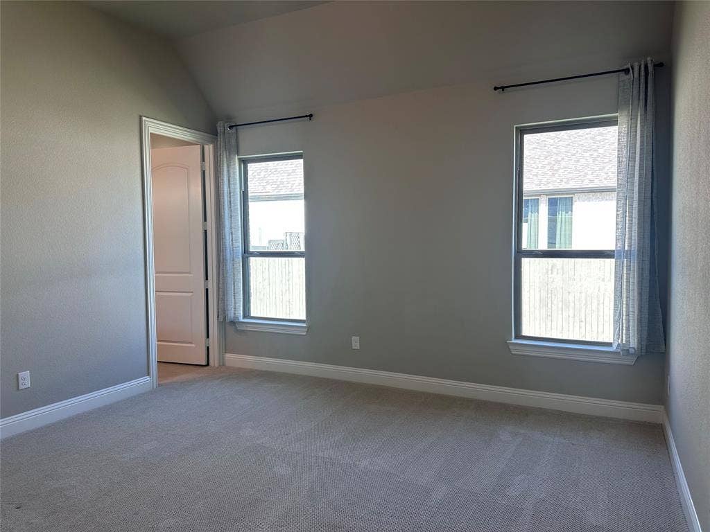 2608 Roaming Trail, Northlake, TX 76247 Vaulted ceiling with textured walls, two windows, wall-to-wall carpeting, and a paneled interior door