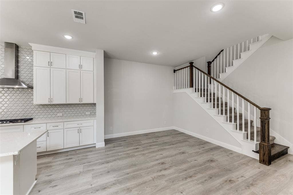 Kitchen with wall chimney range hood, stainless steel gas cooktop, light countertops, decorative backsplash, and recessed lighting