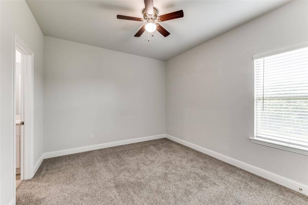 Unfurnished room featuring carpet, a ceiling fan, and healthy amount of natural light