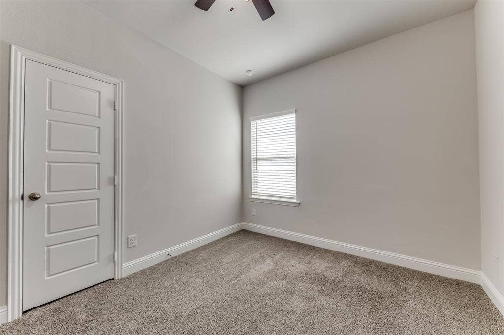 Carpeted spare room featuring a ceiling fan and baseboards