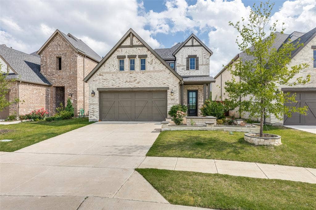 French country style house featuring concrete driveway, a front lawn, brick siding, and a garage