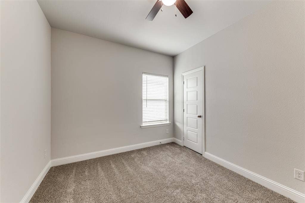 Empty room featuring ceiling fan, light carpet, and baseboards