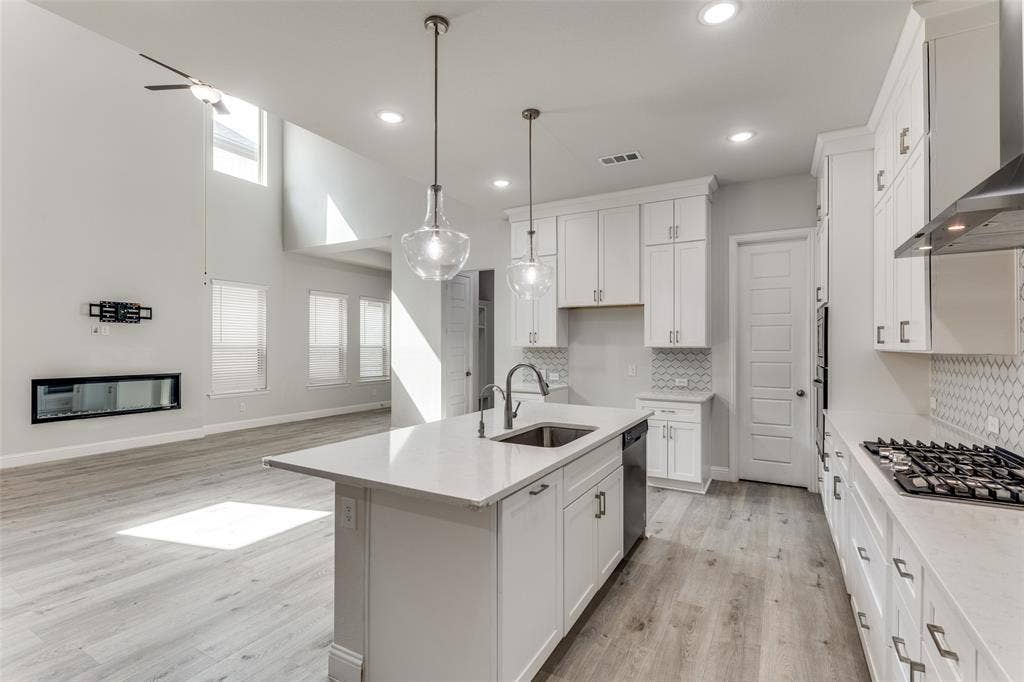 Kitchen with a sink, wall chimney exhaust hood, appliances with stainless steel finishes, healthy amount of natural light, and recessed lighting