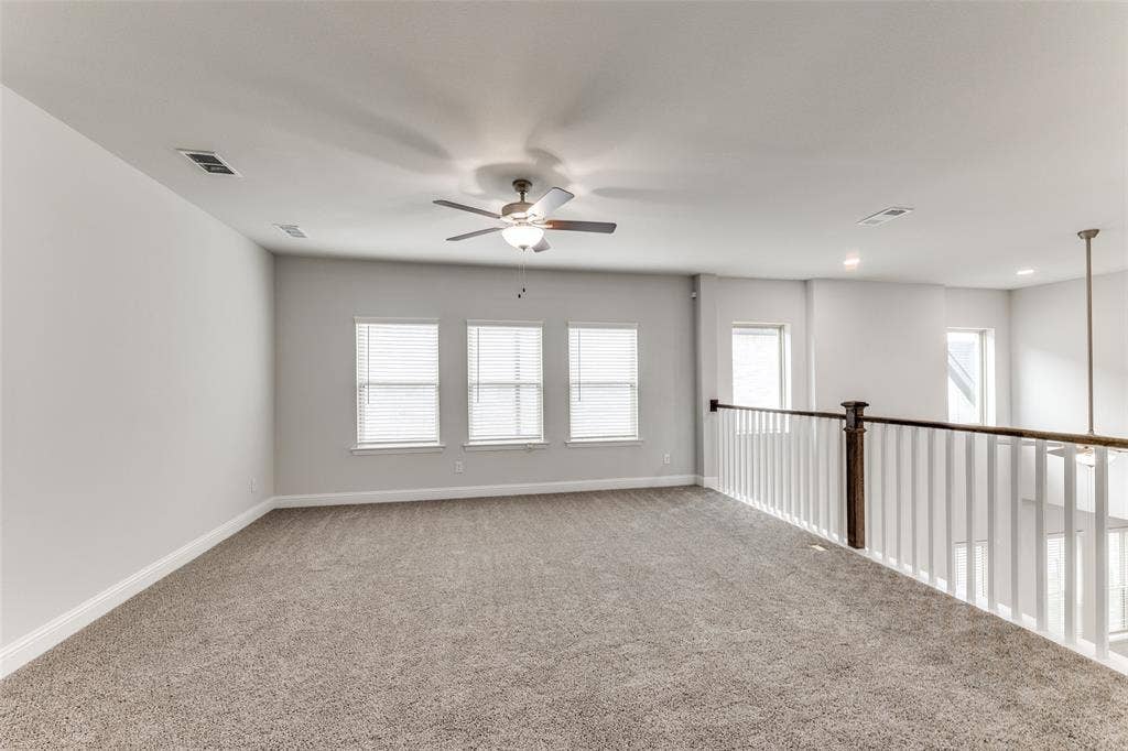 Carpeted spare room with a ceiling fan and baseboards