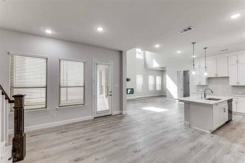 Kitchen featuring open floor plan, dishwasher, light countertops, baseboards, and recessed lighting