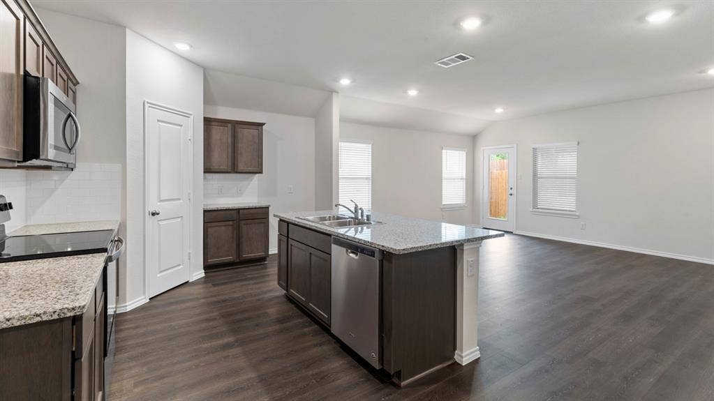 4028 Ripplewood Drive, Lindale, TX 75771 Kitchen island with integrated sink, stainless steel appliances, wood-finish flooring, recessed lighting, and granite countertops