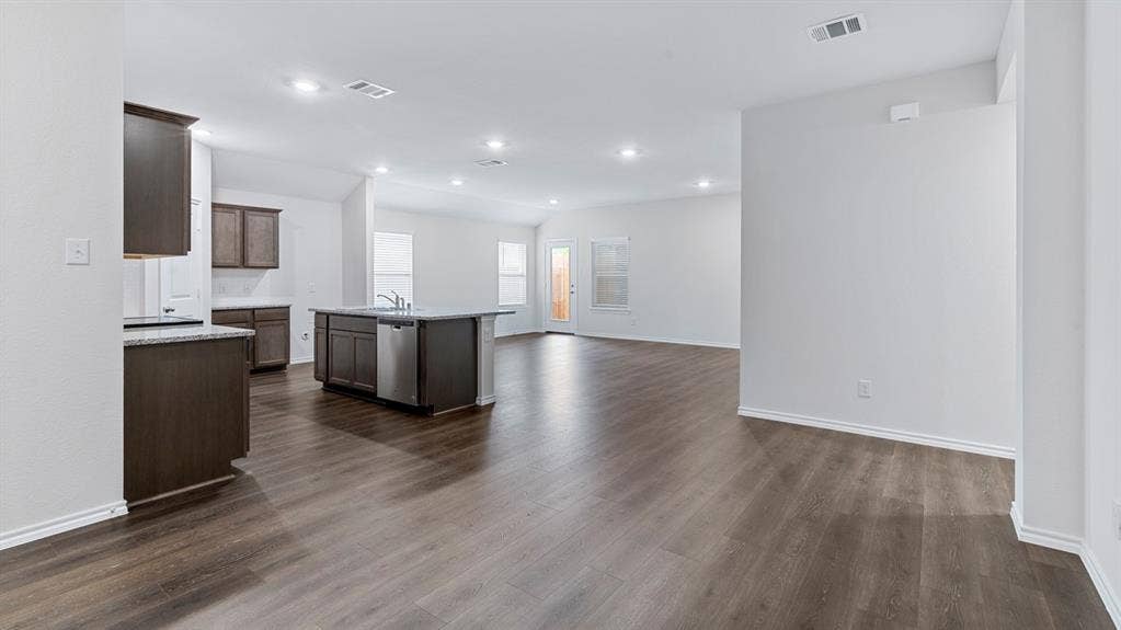 4028 Ripplewood Drive, Lindale, TX 75771 Spacious open-concept layout with wood-finish flooring, recessed lighting, and a kitchen island with built-in appliances